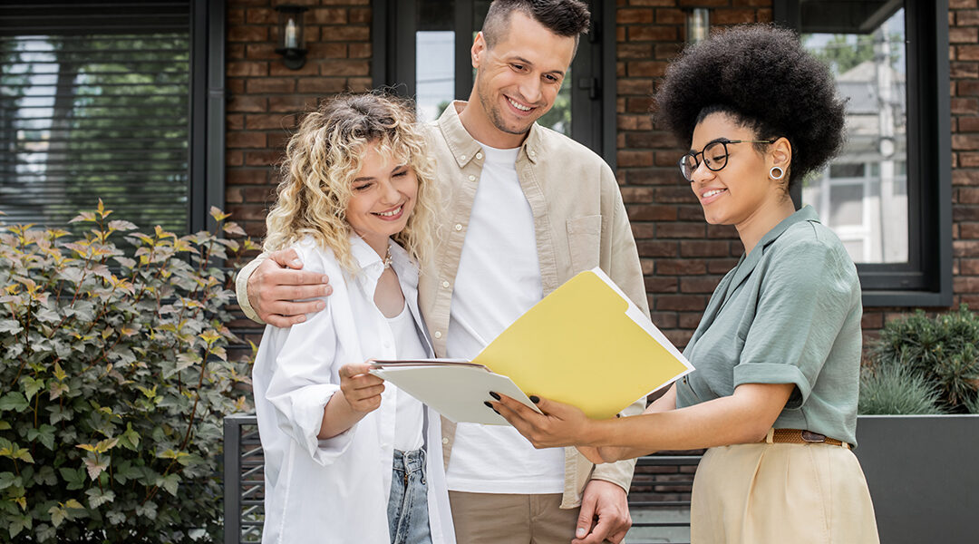 african american property realtor showing documents to happy couple